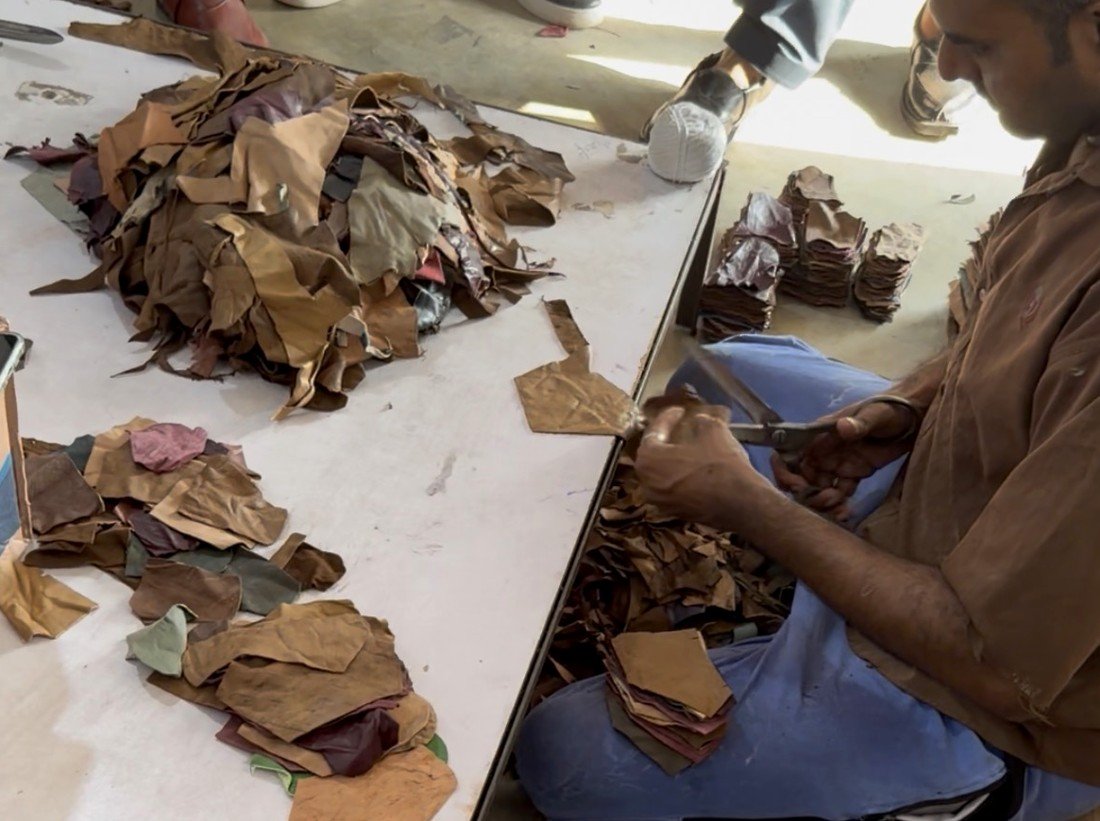 Worker cutting leather components by hand at the factory table